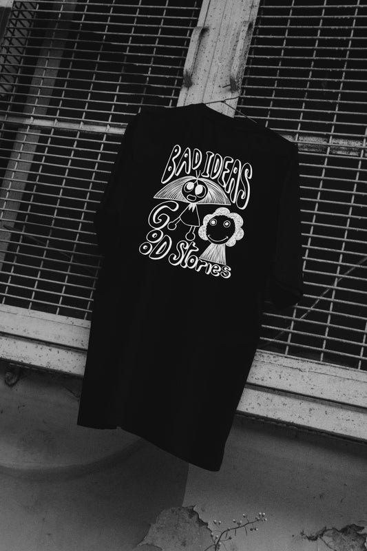 A black t-shirt with a graphic design and the text 'BAD IDEAS' on the front, hanging on a fence.