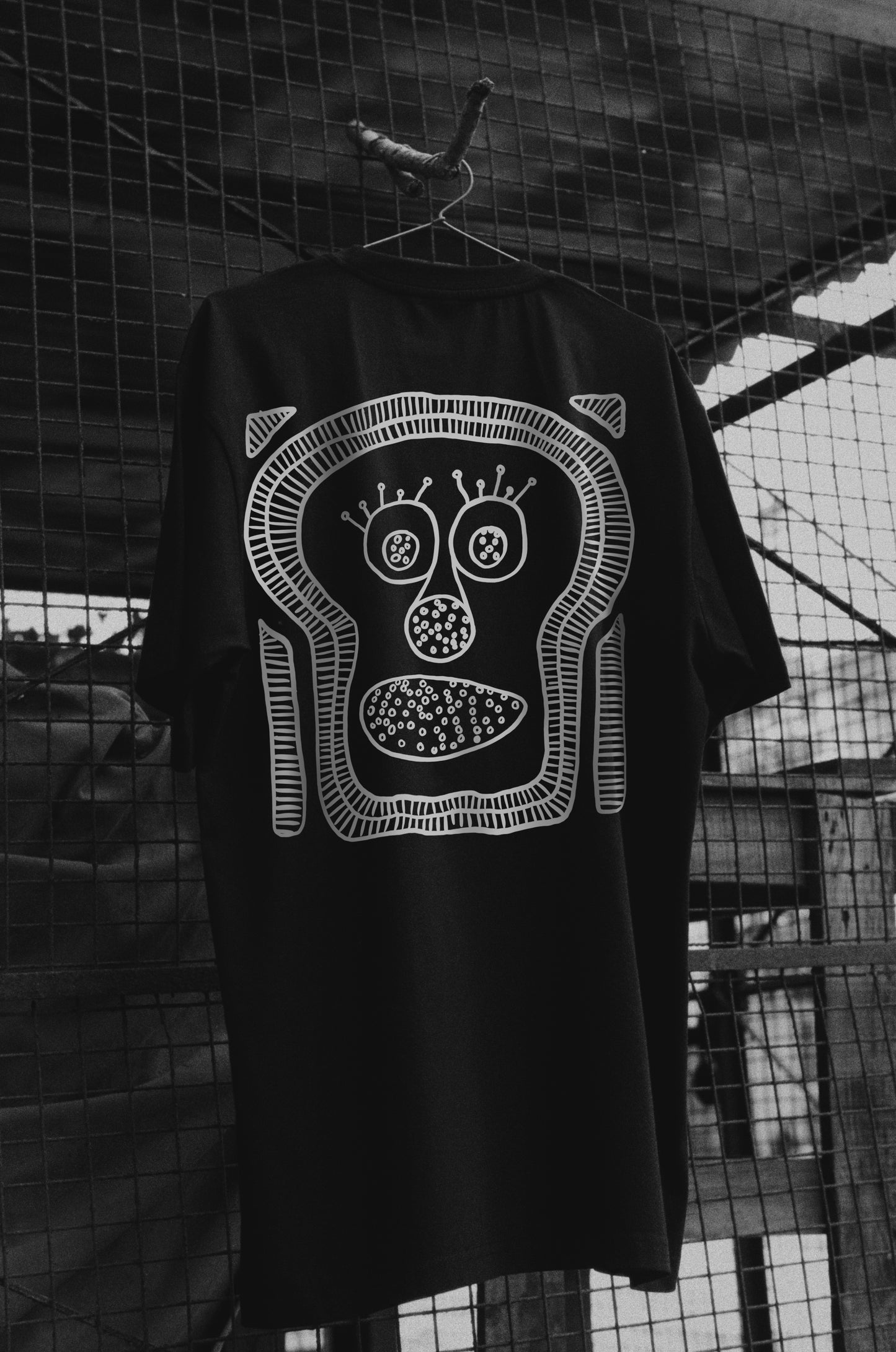 Oversized black T-shirt with a round neck and short sleeves, featuring a white graphic print of a stylized character on the back.